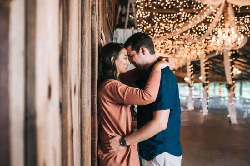 Couple leaning up against a wood grain wall embracing each other at the Wishing Well Barn in Plant City, FL