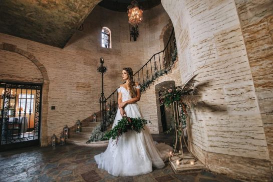Bride standing in the Howey Mansion in Howey-In-The-Hills-Florida beneath a beautiful staircase.